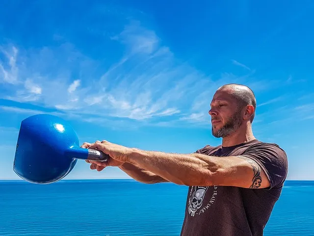 Athlete performing a kettlebell swing outside by the sea